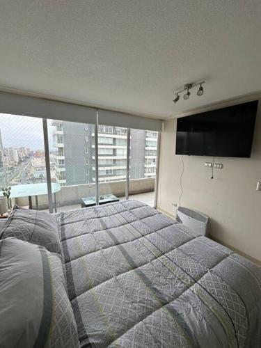 a bedroom with a large bed and a large window at Departamento full equipado in Viña del Mar