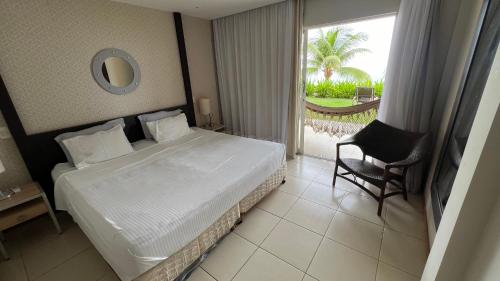 um quarto com uma cama, uma cadeira e uma janela em Loft Lodge - Suíte e Sala em Salvador