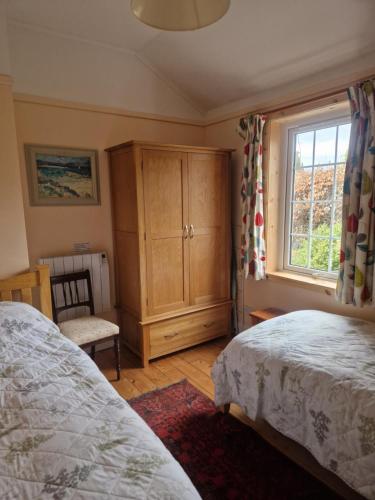 1 dormitorio con 2 camas, armario y ventana en Laich Cottage, en Appin