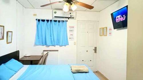 a bedroom with a blue bed and a ceiling fan at Orison Hostels Managua in Managua