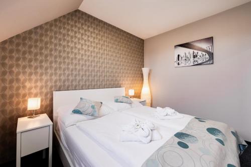 a bedroom with a large white bed with towels on it at Penzión Aqua Maria in Veľaty