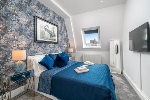 1 dormitorio con 1 cama azul y TV en Niru Experience Royal Deluxe 4BD 2BA Apt en Londres