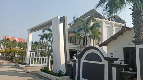 a white house with a gate and palm trees at Kosi Inn Hotel & Resort in Rāmpur