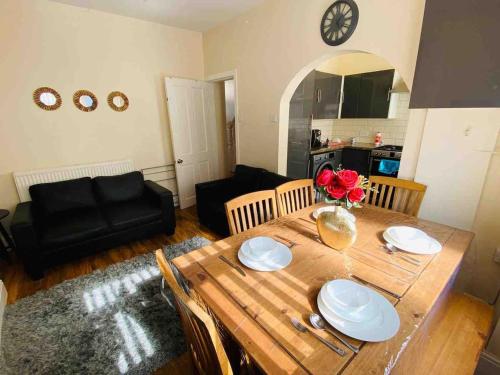 Cozy Retreat Haven في ليفربول: غرفة معيشة مع طاولة خشبية مع لوحات وورود