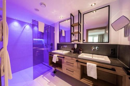 a purple bathroom with two sinks and a shower at Superior Hotel Post Ischgl in Ischgl
