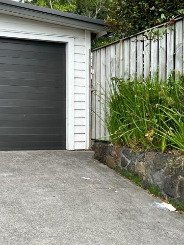 eine Garagentür an einem Haus neben einem Zaun in der Unterkunft Grey Lynn House Auckland in Auckland