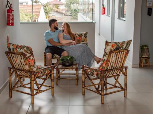 a man and woman sitting on a couch in a living room at Pousada Loft São Chico - Exclusiva para casais in São Francisco do Sul