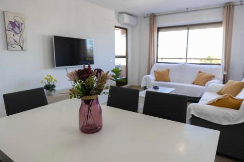 uma sala de estar com um vaso de flores sobre uma mesa em Playa Mucha Vista apto, Parking, Piscina, AC em El Campello