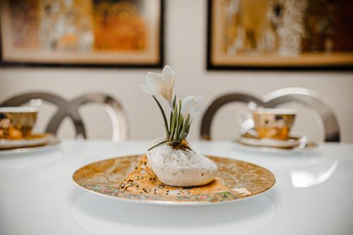 a plate with a vase with flowers in it on a table at Spacious apartment close to Valea Trandafirelor park! in Chişinău