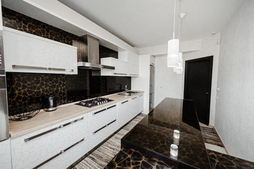 a kitchen with white cabinets and black counter tops at Spacious apartment close to Valea Trandafirelor park! in Chişinău