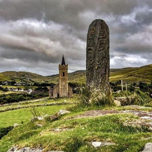 an old church and a stone monument on a hill at An Teach Beag Glencolmcille, little home from home in Glencolumbkille