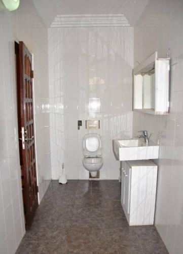 a white bathroom with a toilet and a sink at Tatiana City Appartement in Lomé