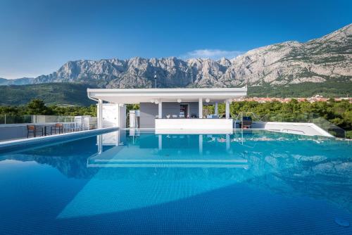 uma casa com piscina com montanhas ao fundo em Boutique Hotel Mirjam em Makarska