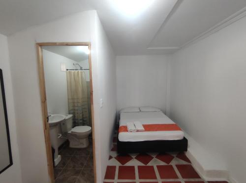 a small bathroom with a bed and a toilet at Cabaña Gaia Rodadero in Santa Marta