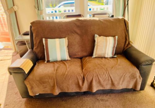 a brown couch with two pillows on it at 40A Oak Village- 2 Bedroom Lodge on Grange Leisure Park in Mablethorpe