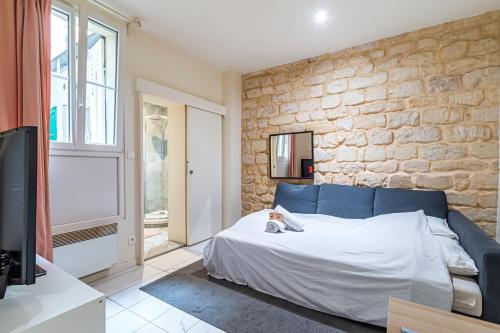 - une chambre avec un canapé bleu et un mur en pierre dans l'établissement Appart Tour Eiffel / Champs de Mars, à Paris
