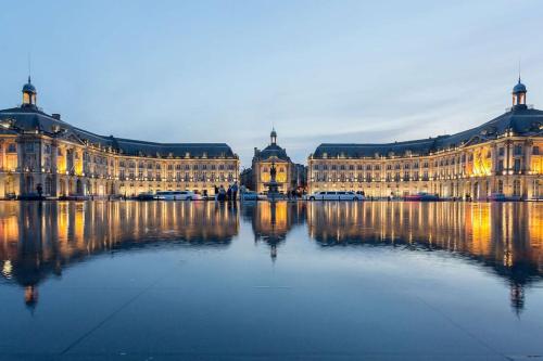 a large building with its reflection in the water at Maison Moderne Piscine Bordeaux in Pessac