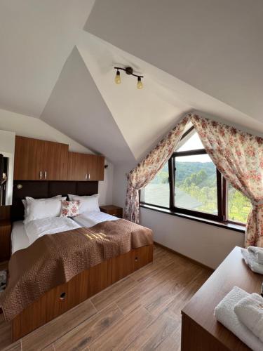 a bedroom with a large bed and a large window at Hanul Doctorului Badeni-Runcu Vila 2 in Fieni