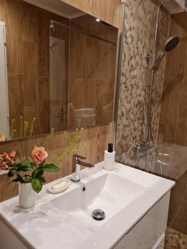 a white bathroom sink with a vase of flowers on it at Happy Home in Valenton