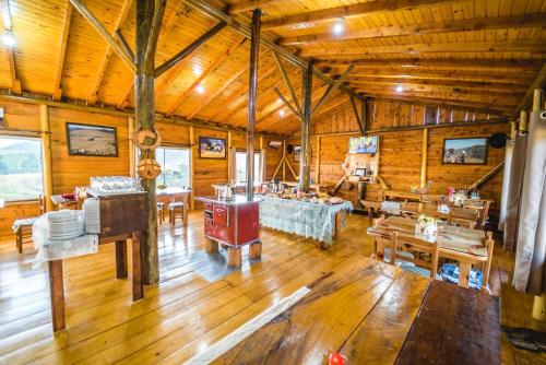 a large room with wooden floors and a room with tables at Costão do Cambará Pousada Fazenda in Cambara do Sul