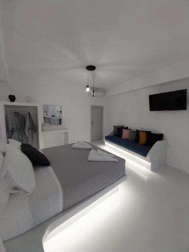 a white bedroom with two beds and a television at East Wind Perissa in Perissa