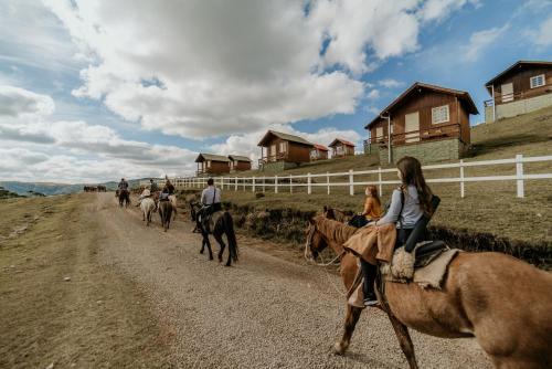 a group of people riding horses down a dirt road at Costão do Cambará Pousada Fazenda in Cambara do Sul