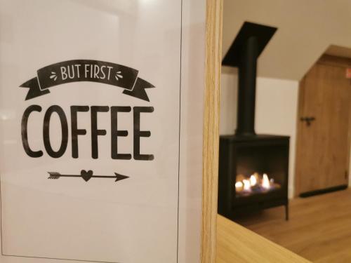 a sign that reads but first coffee in front of a fireplace at B&B Lili's Tuin in Horebeke