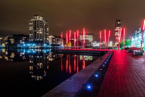 a city at night with red lights in the water at Elegant 2 Bedroom Apartment in Grand Canal in Dublin