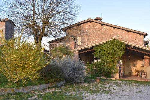 an old brick house with trees and bushes at Agriturismo Poggio ai Legni in Sovicille