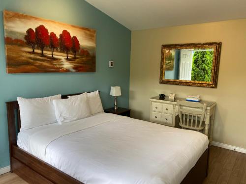 a bedroom with a white bed and a mirror at Motel des Cèdres in Sherbrooke