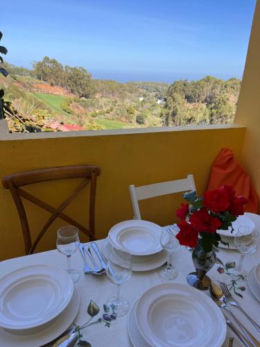 Casa Rural Los Tilos Betancor في Moya: طاولة عليها صحون و كؤوس نبيذ و ورد