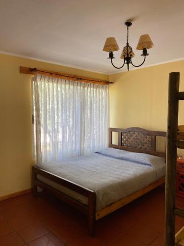 a bedroom with a bed with a window and a chandelier at Casaelqui in Vicuña