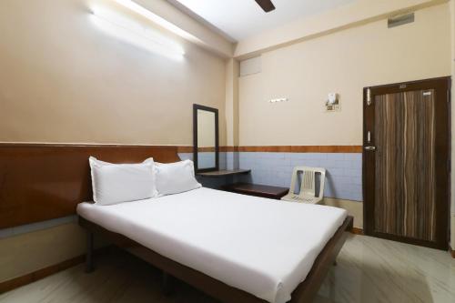a bedroom with a large white bed and a wooden door at OYO Jayanthi Mansion in Chennai