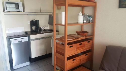 een keuken met houten rekken en een magnetron bij Résidence Parc Et Avenue Dominica - 2 Pièces pour 4 Personnes 324 in Le Barcarès
