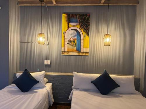 duas camas num quarto com dois candeeiros e um quadro em Maloka Boutique Hostel em Cartagena das Índias