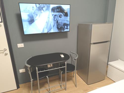 a kitchen with a table and a tv on the wall at Residenza delle Nazioni in Gatteo a Mare