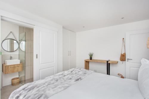 a white bedroom with a large bed and a mirror at GrottoOnTheRocks in Grotto Bay