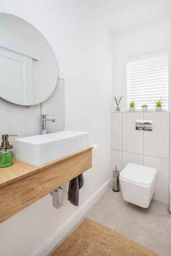 a white bathroom with a sink and a toilet at GrottoOnTheRocks in Grotto Bay