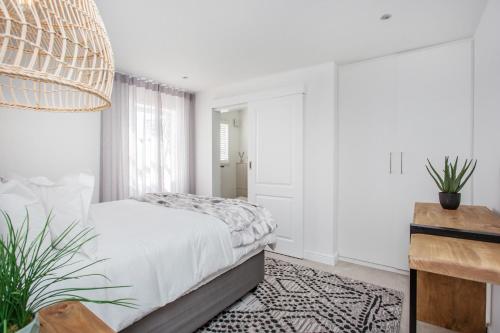 a white bedroom with a bed and a potted plant at GrottoOnTheRocks in Grotto Bay