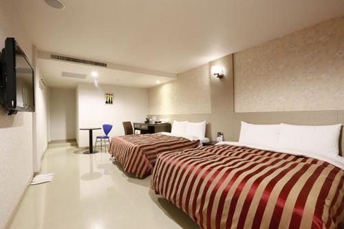 Habitación de hotel con 2 camas y escritorio en Hua Xiang Motel - Arena, en Kaohsiung