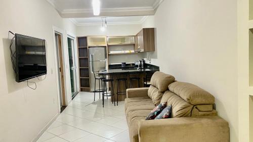 a living room with a couch and a kitchen at Casa de 2 QUARTOS COM PISCINA in Balneário Camboriú