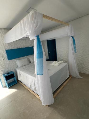 ein Schlafzimmer mit einem weißen Bett mit Baldachin in der Unterkunft KEFI POUSADA in Maragogi