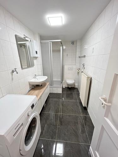een badkamer met een wasmachine, een wastafel en een toilet bij Zentrale Wohnung I 5G Internet I Netflix I in Iserlohn