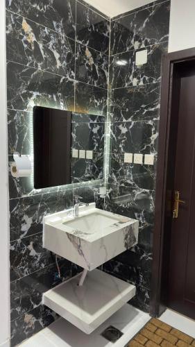 bagno in marmo nero con lavandino e specchio di فندق الاقامه السعيده a Al Bad‘