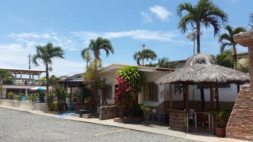 a house with a straw umbrella and palm trees at El Remanso in Tonsupa