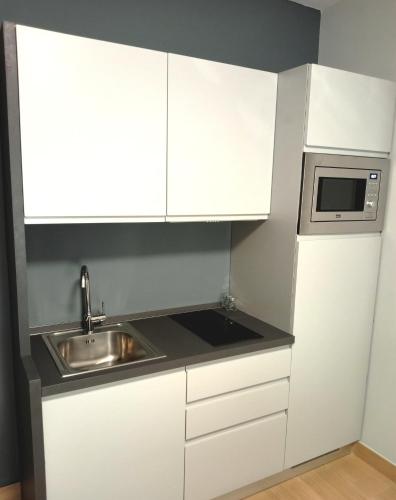 a white kitchen with a sink and a microwave at Residenza delle Nazioni in Gatteo a Mare