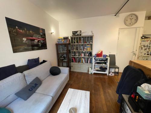 un salon avec un canapé et une horloge au mur dans l'établissement Apt 4personnes idéal pour les JO, à Boulogne-Billancourt