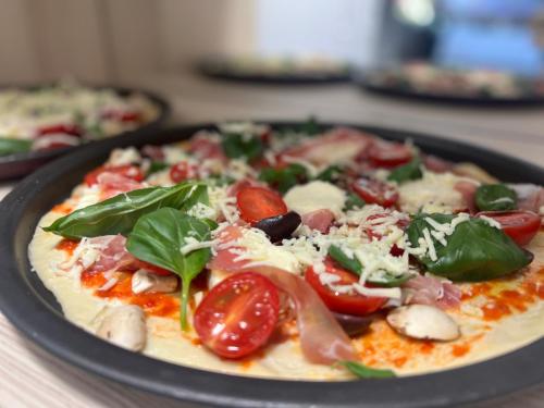 a pizza with tomatoes and basil on a table at Hanul Doctorului Badeni-Runcu Vila 2 in Fieni