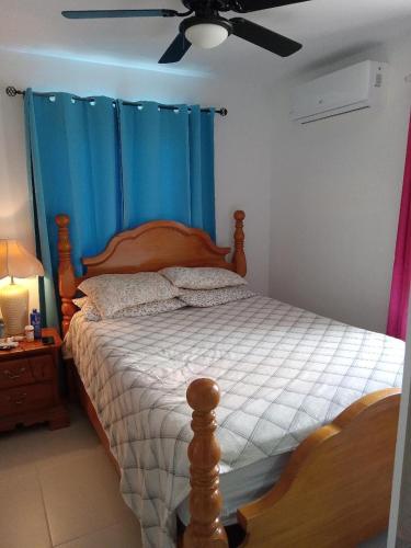 um quarto com uma cama com cortinas azuis e uma ventoinha de tecto em Crisfer Punta Cana em Punta Cana