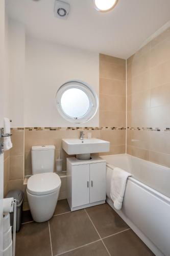 a bathroom with a toilet and a sink and a tub at Perfect Belfast Stay, 2 Bedroom, Parking, Walkable by StayByNumbers in Belfast